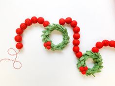 some red beads and green wreaths on a white surface with yarn in the shape of letters o