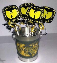 a bucket filled with yellow and black cupcakes on top of a white table