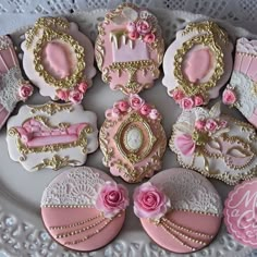 pink and gold decorated cookies are on a white platter with lace doily around them