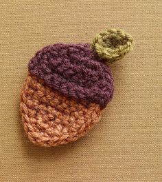 a crocheted hat with a green and brown pom - pom on top