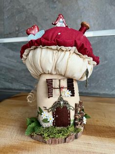 a small mushroom house with a red hat on it's head sitting on top of a wooden table