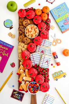 a table topped with lots of different types of food next to books and pencils