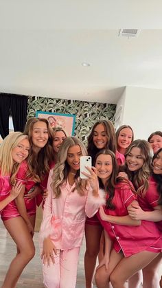 a group of women in pink outfits posing for a photo with one woman taking a selfie