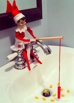 an elf sitting on top of a sink with a toothbrush