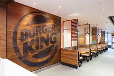 a burger king restaurant with wooden signs on the wall and chairs in front of it