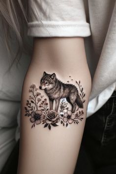 a woman's thigh with a wolf and flowers tattoo on the side of her leg