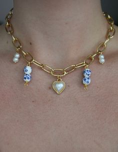 Our Charmed Chained Necklace includes three different charms. The center piece being a beautiful charmed heart with rimmed gold. The other including two pearl charms on each side. As well as two porcelain beads on both sides of the heart charm. The necklace has an adjustable clasp which allows you to adjust the necklac