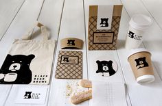 coffee cups, cookies and paper bags on a white wooden table with bear stickers