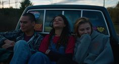 three people sitting in the back of a pick up truck with their heads turned to look up