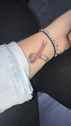 a woman's arm with a tattoo on it that has a red and black arrow