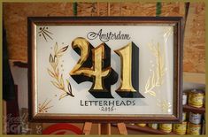 a framed sign with the number twenty four in gold and black, on an easel