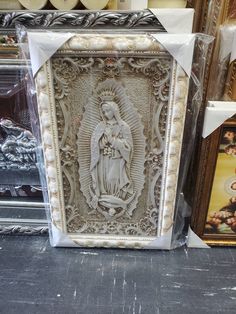 an image of the virgin mary on display in a store window with other items behind it