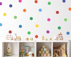 colorful polka dot decals on the wall above shelves in a playroom with toys