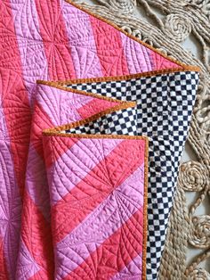 two pink and black quilts are laying next to each other on a piece of cloth