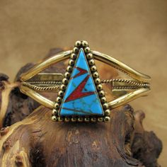 Brass and turquoise inlay cuff bracelet. This bracelet is 1 3/8" wide. The center pendant is inlaid with turquoise and coral.  The inlay is 1 1/8" tall x 3/4" wide. A row of brass beads surrounds the inlay. The inside measures 6 1/2" including the 1" opening.  There is a row of twisted brass wire rope between the two bands of the cuff. The bracelet is in good condition. Thank you for looking. Please let us know if you have questions.  BT-6 k *The color you see on your screen may not reflect the Brass Cuff Bracelet, Brass Cuff, Turquoise And Coral, Brass Beads, Cuff Bracelet, Turquoise Ring, Turquoise Bracelet, Stone Color, Cuff Bracelets