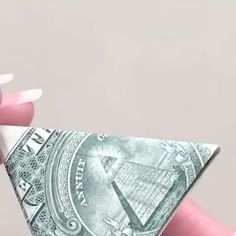 a person holding up a money bill in their left hand and the other hand is pointing at it