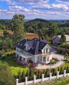 an aerial view of a large white house in the middle of a lush green field