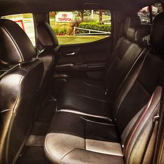 the interior of a car with black leather seats and an open front door, looking out onto a street