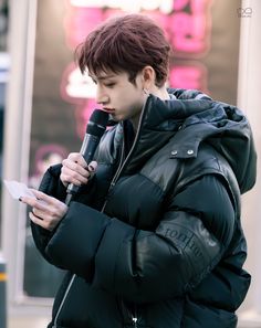 a young man holding a microphone while standing next to a building