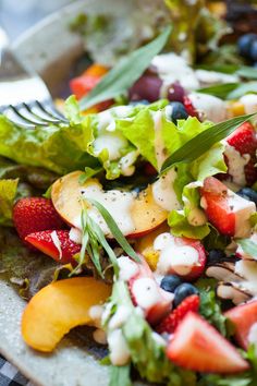 a close up of a plate of food with fruit and salad dressing on it's side