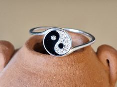 This tiny delicate ring is a beautifully crafted sterling silver piece, one centimeter in diameter, showcasing a unique interpretation of the Yin Yang symbol.  The delightful black and white design decorated with over 9 tiny crystals makes an ideal gift or treat yourself. This distinctive pendant is a harmonious blend of natural beauty and artistic design, making it a standout accessory.  MATCHING NECKLACE HERE: https://www.etsy.com/uk/listing/1660404741/tiny-ying-yang-crystal-sterling-silver?cl Symbolic Sterling Silver Stackable Rings For Anniversary, Symbolic Adjustable Rings As Gifts, Dainty Adjustable Stackable Rings, Hallmarked, Dainty Adjustable Hallmarked Stackable Rings, Symbolic Sterling Silver Stackable Rings, Dainty Hallmarked Stackable Rings, Dainty Round Stackable Rings Hallmarked, Spiritual Silver Stackable Rings For Gift, Symbolic Round Stackable Jewelry