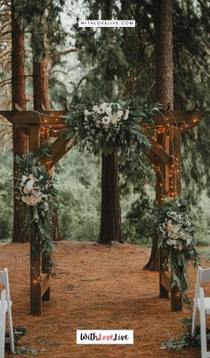 an outdoor ceremony setup with white flowers and greenery on the arbor, surrounded by trees