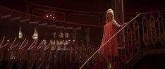 a group of women in red dresses standing on stairs