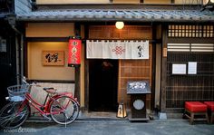 a red bike parked in front of a building with japanese writing on the door and windows