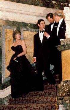 two men and a woman in formal wear walking up stairs