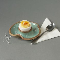 an egg is sitting on a plate next to a spoon