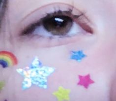 a close up of a person's face with colorful stars on their forehead and eyes