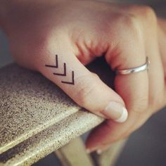 a woman's hand with a small tattoo on her left thumb and an arrow