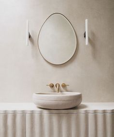 a white sink sitting under a mirror next to a wall mounted faucet in a bathroom