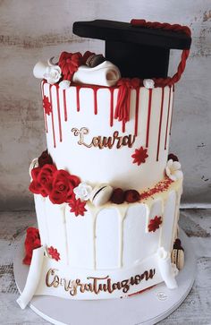 a graduation cake is decorated with red and white icing, roses, and mortars