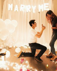 a man kneeling down next to a woman on the floor with balloons and confetti