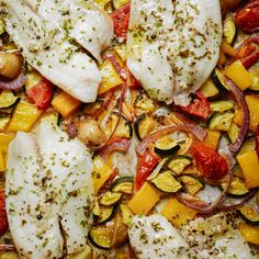 some fish and vegetables on a pan with seasoning sprinkled on top for garnish