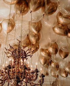 a chandelier with many balloons hanging from it's ceiling in a room