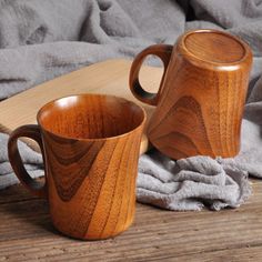 two wooden mugs sitting next to each other on top of a wood tablecloth