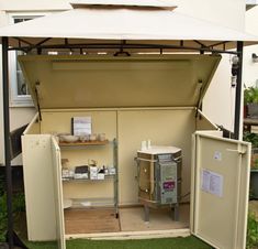 an open storage area in the back of a house with grass on the ground and other items inside