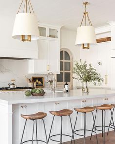 a kitchen with four stools and an island in the middle, surrounded by white cabinets