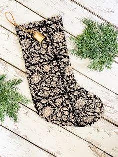 an oven mitt sitting on top of a wooden table next to pine cones and greenery