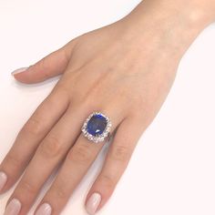 This ring is reminiscent of Princess Diana and Kate's royal cocktail engagement ring. Handcrafted cocktail ring holds a Ceylon cushion cut sapphire 12.28 ct center stone. It is surrounded by round white natural diamonds 3.20 ct. Diamonds are natural and white in G-H Color Clarity VS. Platinum 950 metal. Length: 1.5 cm Width: 1.9 cm Weight: 10.2 g [shortcode] [video] [/video] [/shortcode]