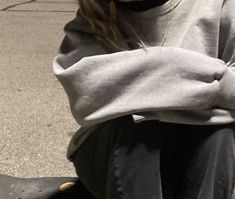 a woman sitting on top of a black skateboard