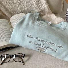 Introducing the "Shhh... I'm on a date with my book boyfriend" Book Boyfriend Sweatshirt, the perfect addition to your pop of color to your outfit and can make you stand out in a crowd. The "Shhh... I'm on a date with my book boyfriend" Book Boyfriend Sweatshirt is a cozy reading sweatshirt, perfect for curling up with your favorite book. The sweatshirt is designed to keep you warm and comfortable while you read, making it an ideal choice for chilly evenings. The sweatshirt is made from organic cotton, which is a more sustainable and eco-friendly choice compared to regular cotton. This means that you can feel good about your purchase while enjoying the comfort and style of this sweatshirt. The minty green color of the sweatshirt is a great way to add a pop of color to your outfit. It can m Book Shirts Aesthetic, Booktok Sweatshirts, Book Hoodies, Reading Outfits, Book Sweatshirts, Reading Sweatshirt, Boyfriend Sweatshirt, Bookworm Gifts, Book Merch