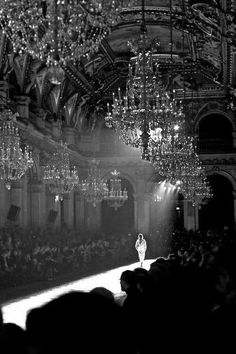 a black and white photo of a runway with chandeliers hanging from the ceiling