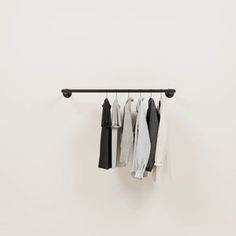 clothes hanging on a rail in front of a white wall