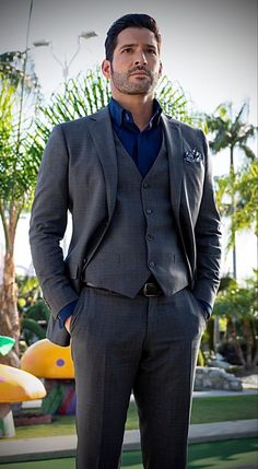 a man wearing a suit and tie standing in front of a playground area with palm trees