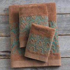 three brown towels with blue designs on them sitting on top of a wooden table next to a bottle of wine