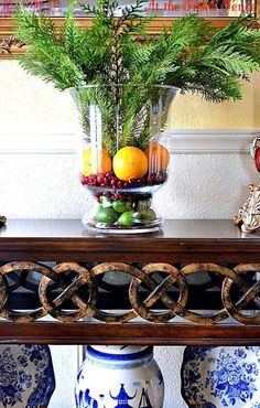 a vase filled with fruit sitting on top of a table next to two blue and white vases