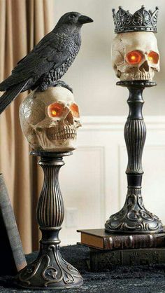 a bird sitting on top of a skull next to two candles with skulls in them